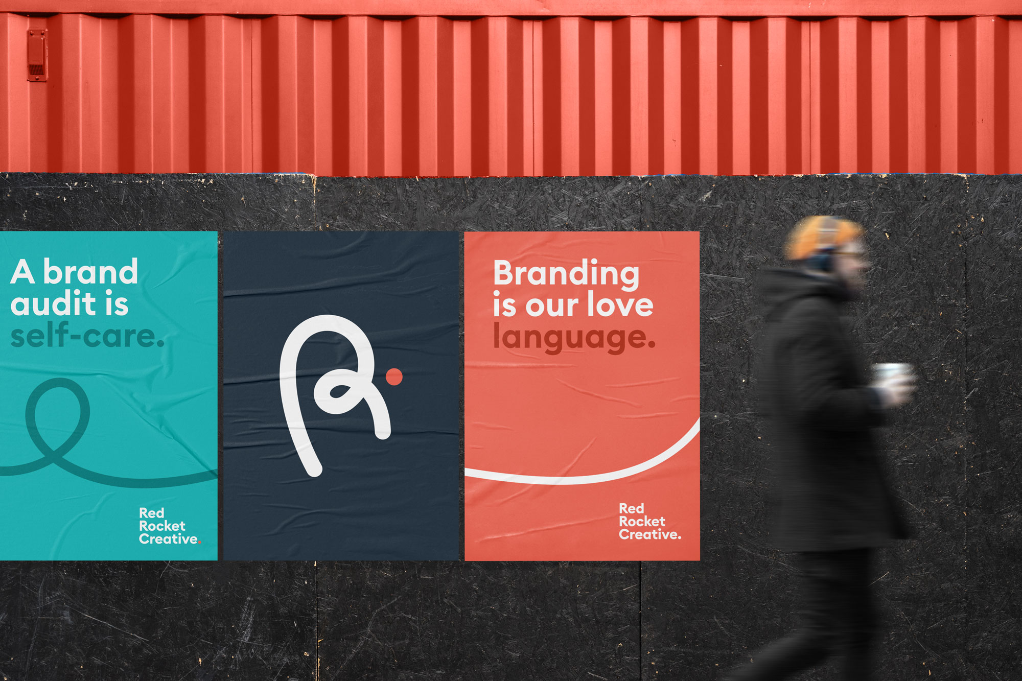 Man walking past a wall with three Red Rocket Creative posters.